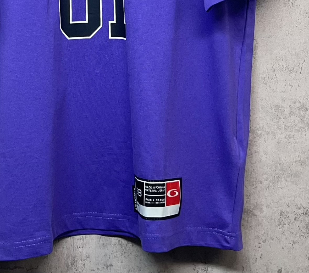 Purple T-shirt hem with red-and-white label patch