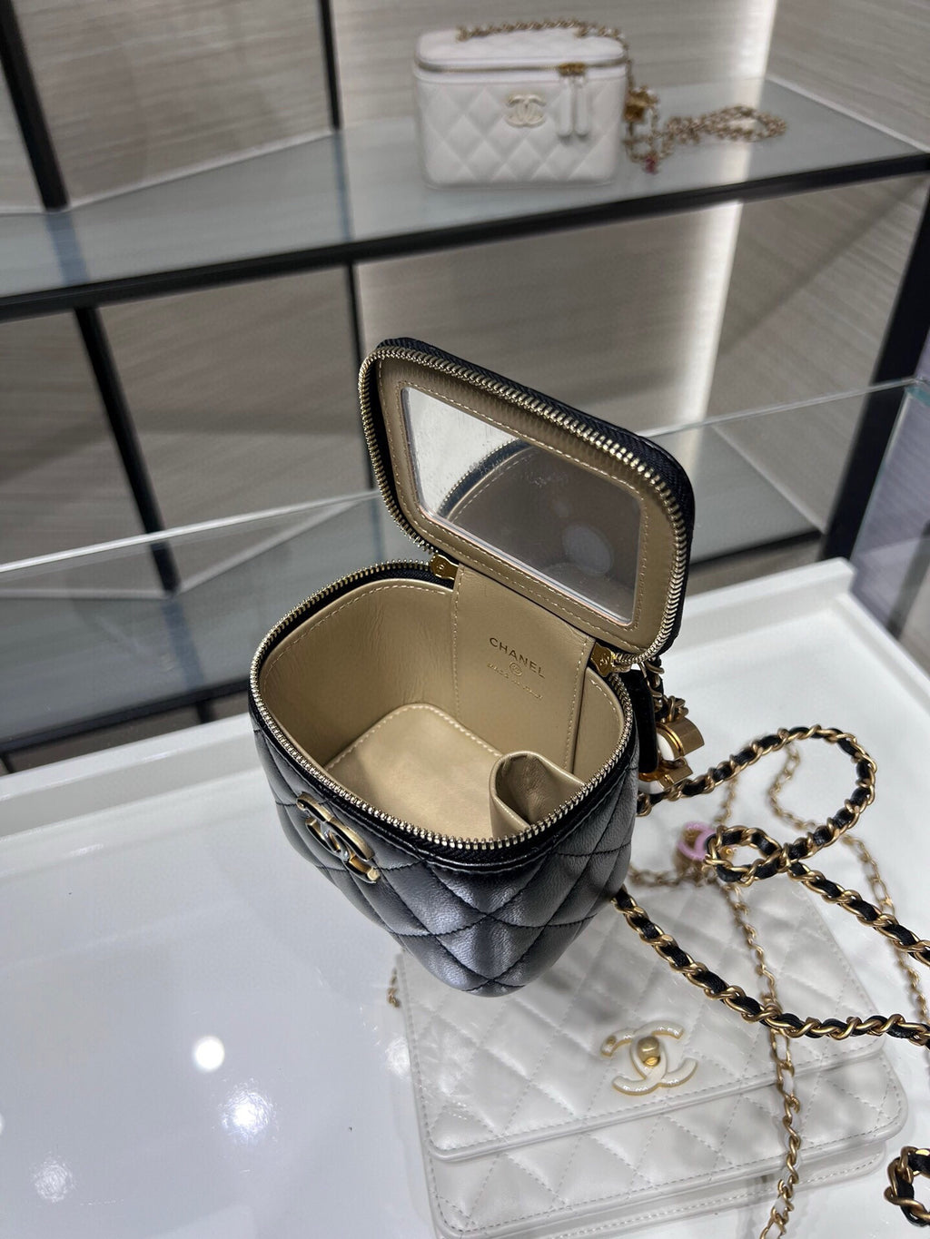 Chanel mini quilted bag open with gold chain strap and beige interior, black