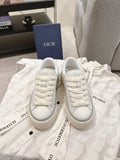 White unisex Dior low-top sneakers with lace-up front and rubber sole
