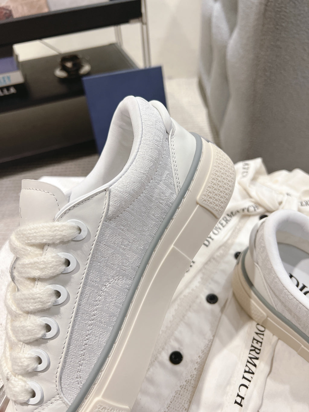 White Dior low-top sneaker side view with perforated-texture fabric panel