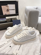 White Dior low-top sneakers on display, lace-up with textured sidewall