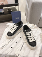 Pair of unisex low-top sneakers, dark gray uppers with white laces and logo detail
