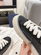 Unisex sneaker side view: dark upper with white laces, off-white sole edge, stitched trim