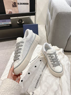 Low-top Dior sneakers pair, white uppers with gray laces and chunky rubber sole