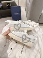 Low-top Dior sneakers, front view with gray V graphic and lace-up design