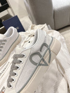 Low-top Dior sneakers, side view with gray V logo and lace-up vamp