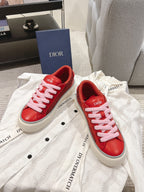 Pair of red Dior low-top sneakers with pink laces on white garment