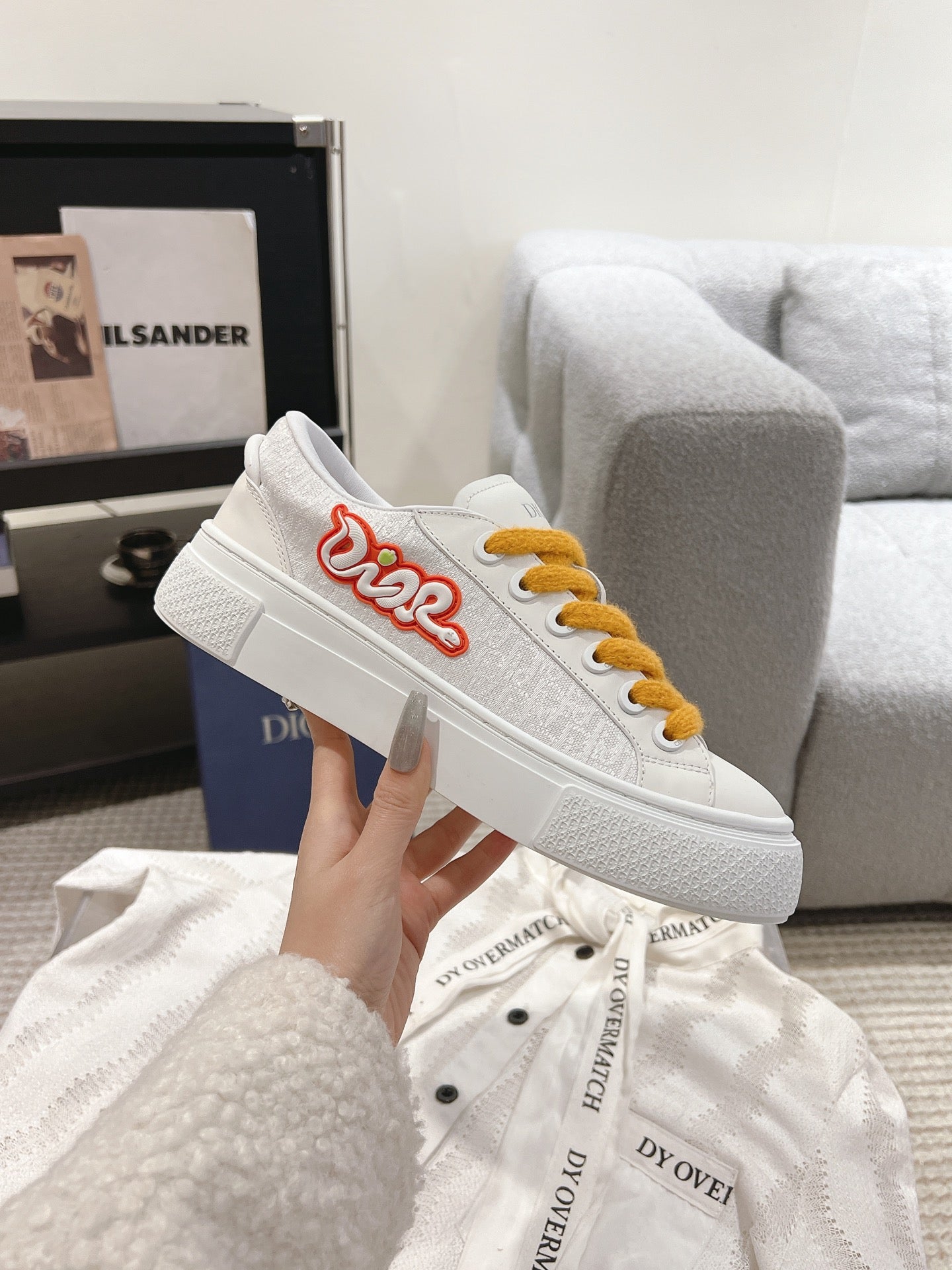 White Dior low-top sneaker with mustard laces and red heart logo