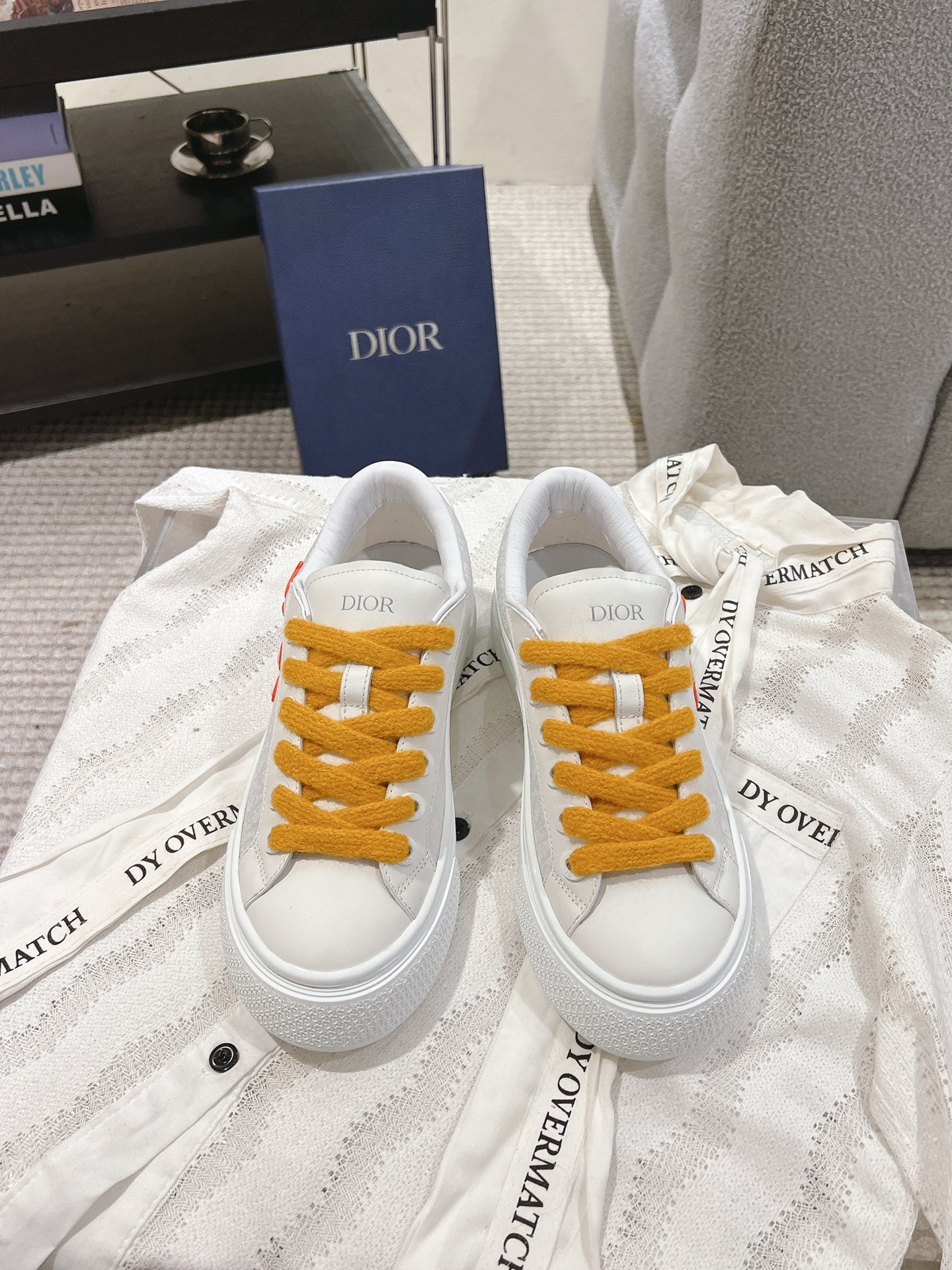 White Dior low-top sneakers with mustard lace-up front and logo on tongue