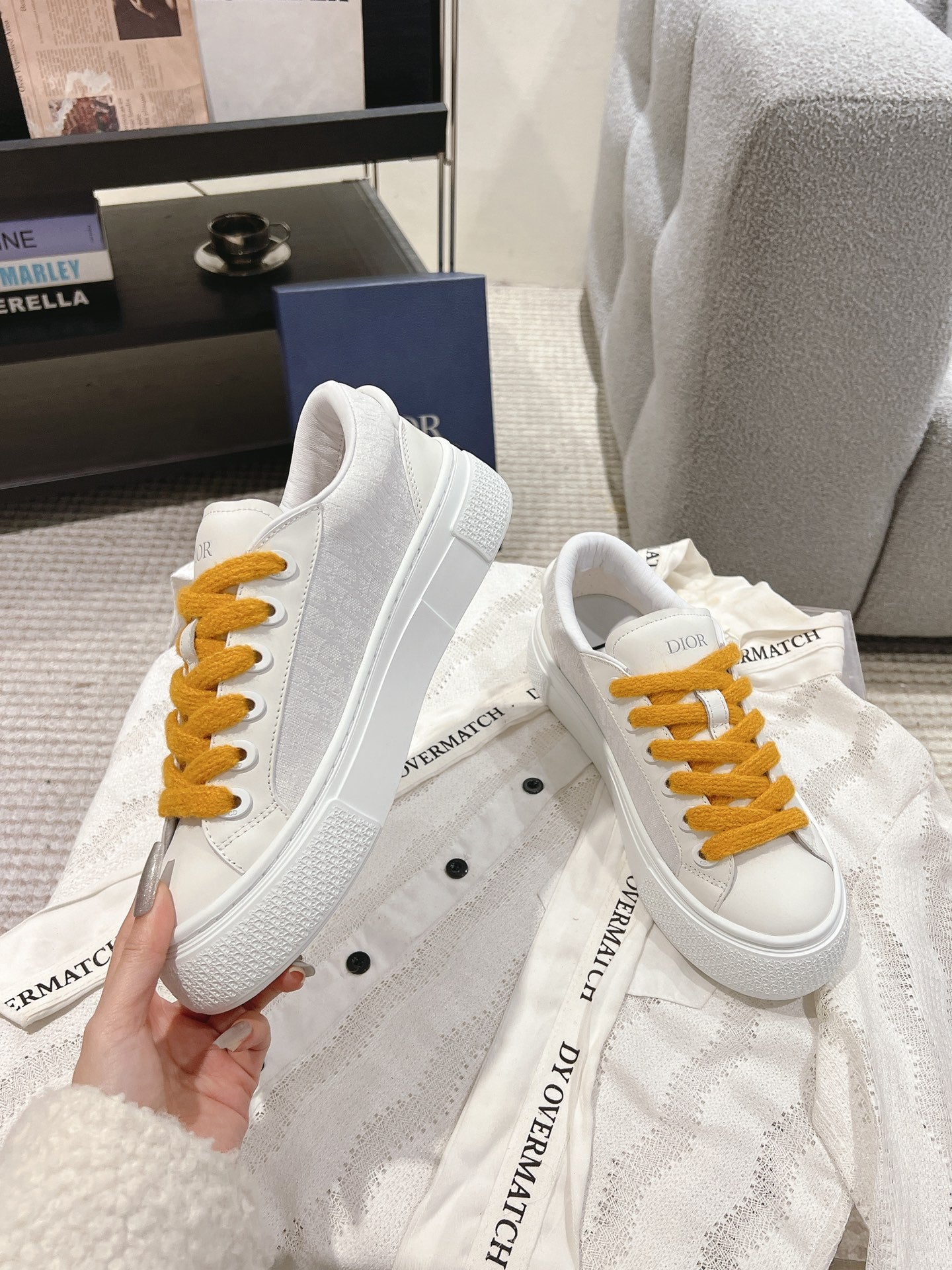White Dior low-top sneakers with mustard laces and lace-up eyelets