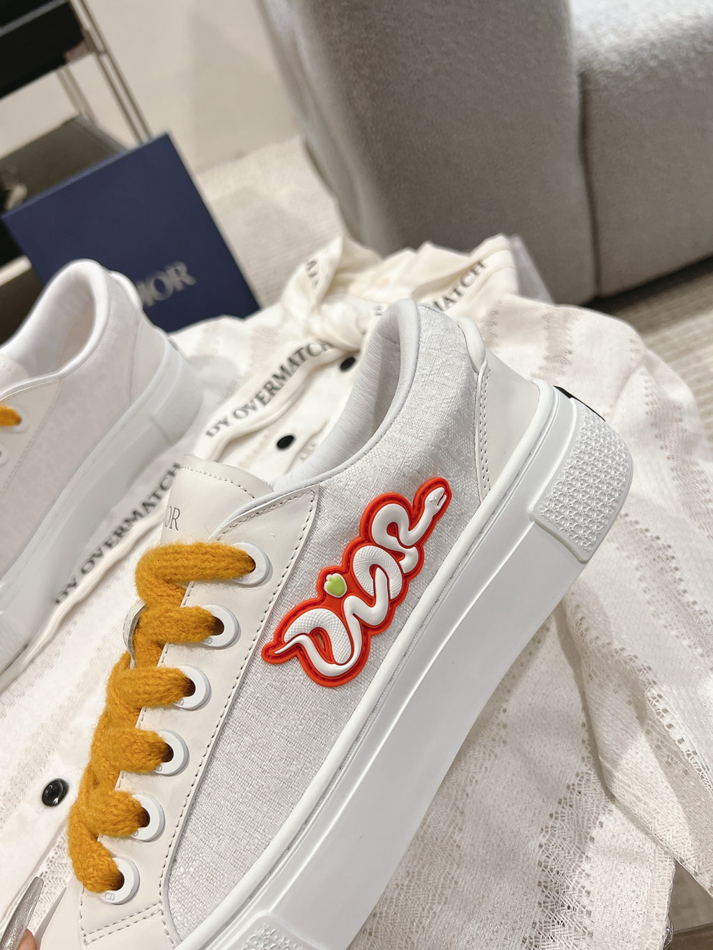 White Dior sneaker with side red Dior logo and mustard laces