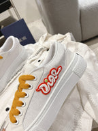 White Dior sneaker with side red Dior logo and mustard laces