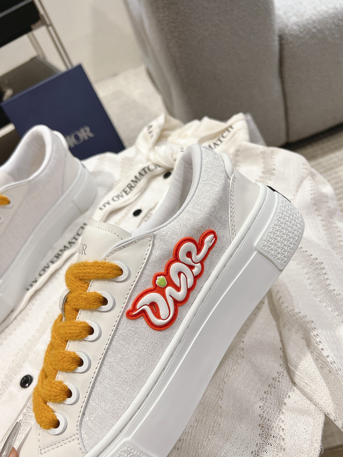 White Dior sneaker with side red Dior logo and mustard laces