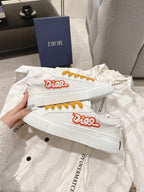 White Dior sneakers with red logo and mustard laces, side view