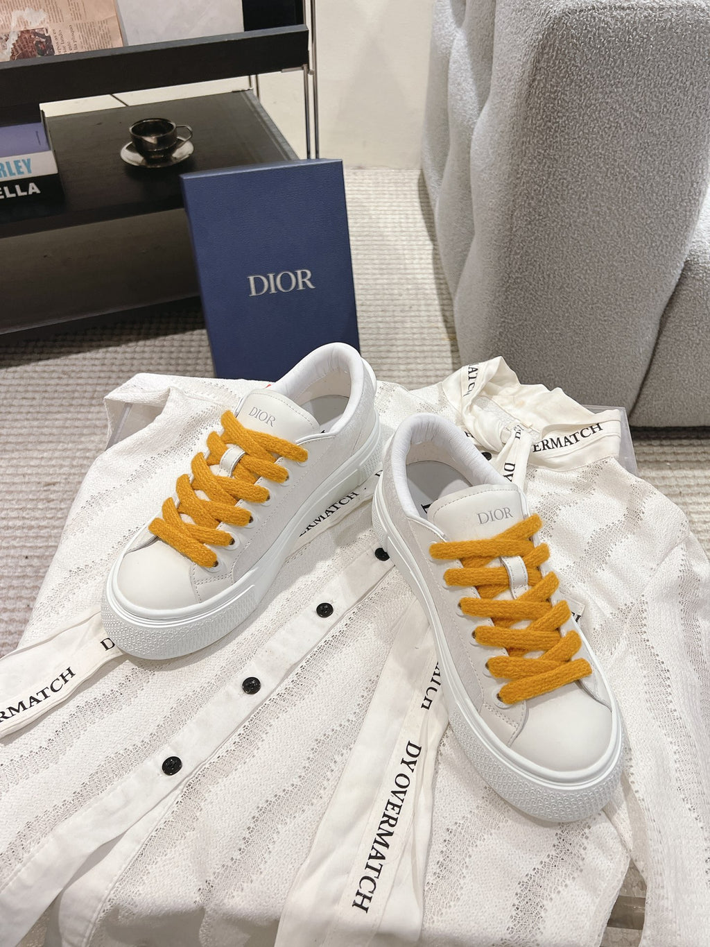White Dior lace-up sneakers with mustard laces on white textured fabric