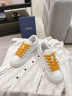 White Dior lace-up sneakers with mustard laces on white textured fabric