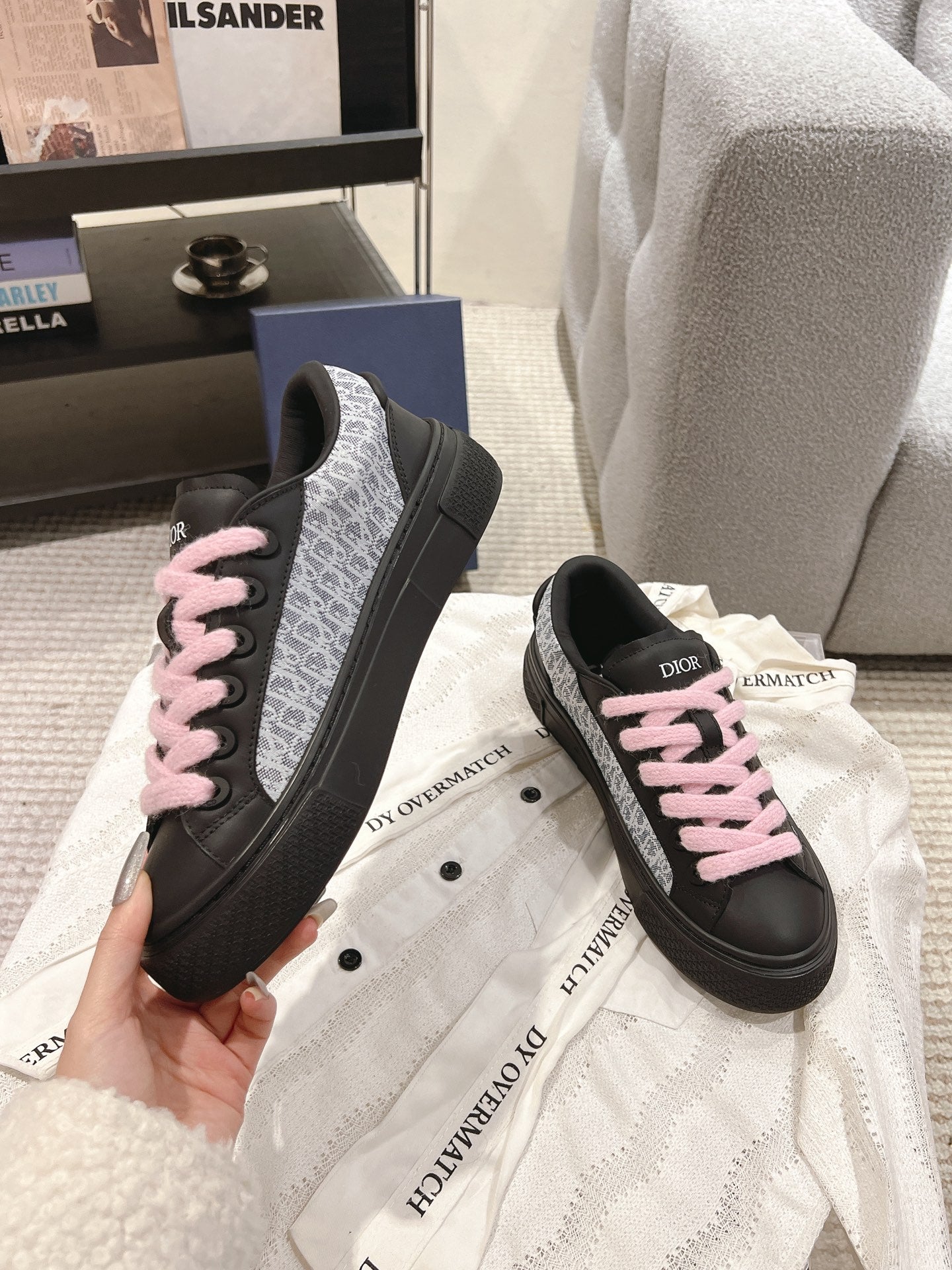 Black low-top sneakers with pink laces on white fabric with repeating text accents