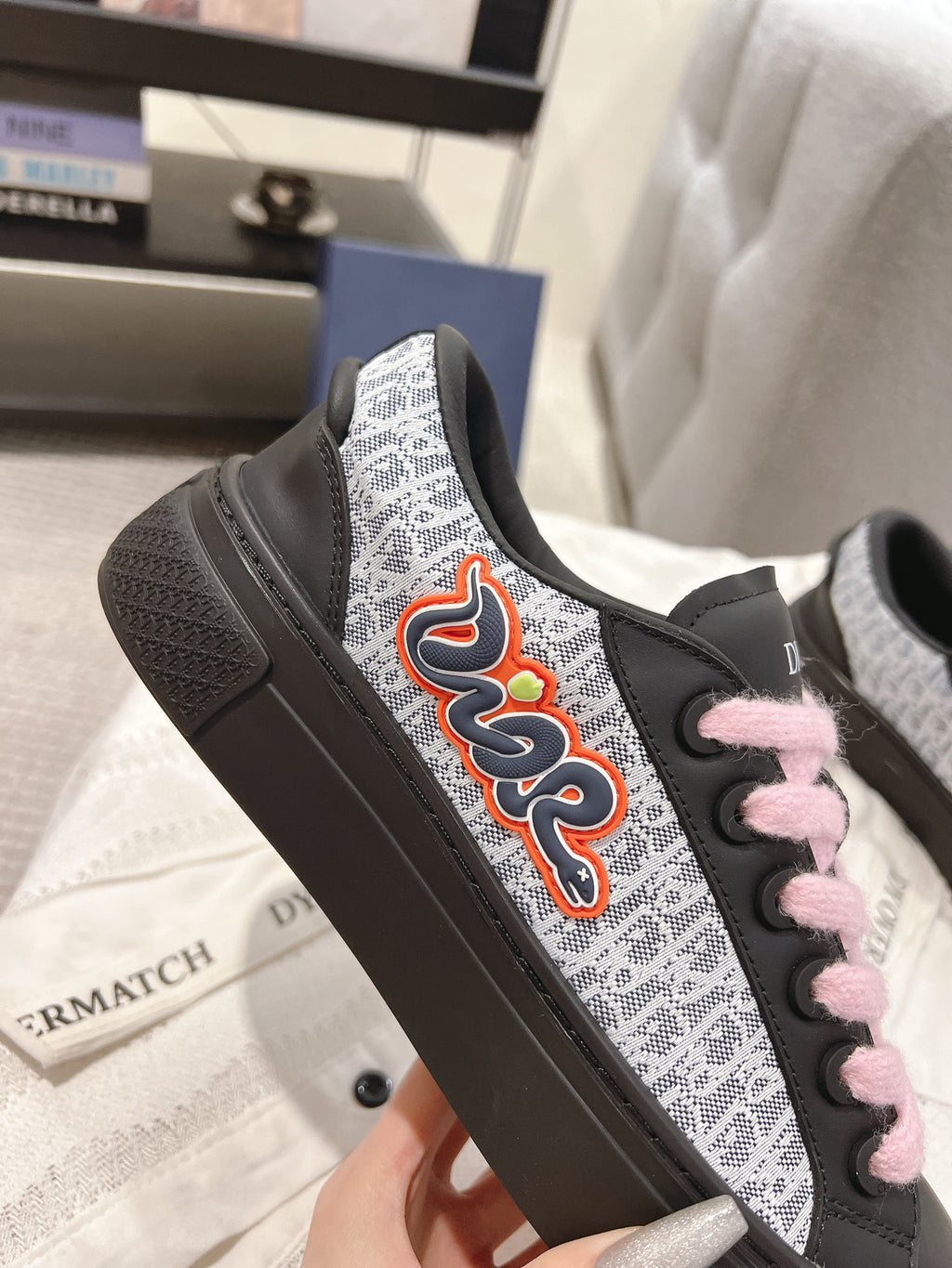 Black low-top sneaker with pink laces and colorful side emblem on patterned panel