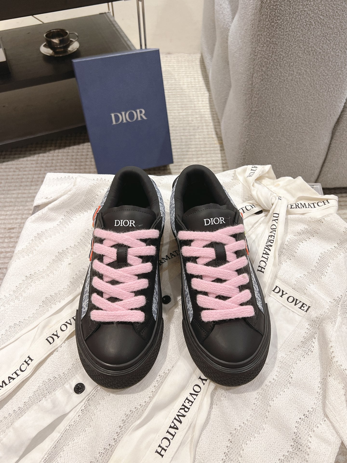 Black low-top sneakers with pink lace-up ties and Dior-branded heel tabs