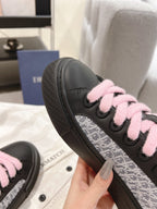 Black low-top sneaker with pink laces and textured sidewall detail view