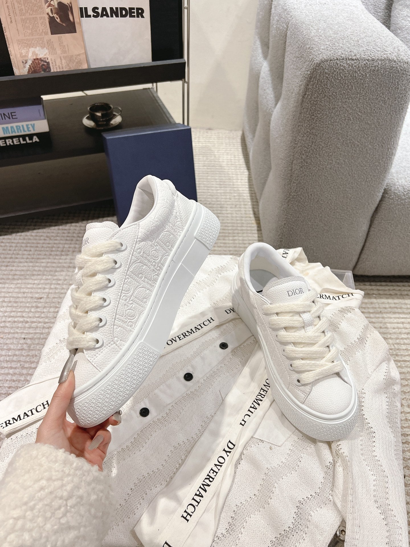 White low-top sneakers with lace-up front, textured sole, and logo tongue label