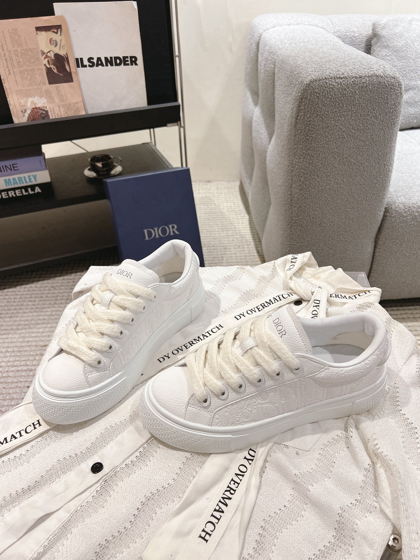 Pair of white low-top lace-up sneakers with textured panels and logo print