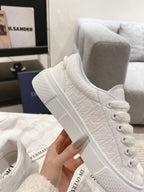 White low-top sneaker with lace-up front and textured side panels