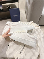 White lace-up low-top sneakers laid flat with textured pattern and flat sole