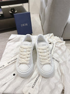 White low-top sneakers with lace-up front and printed logo straps