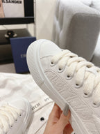 Close-up of white low-top sneaker toe with lace holes and textured upper