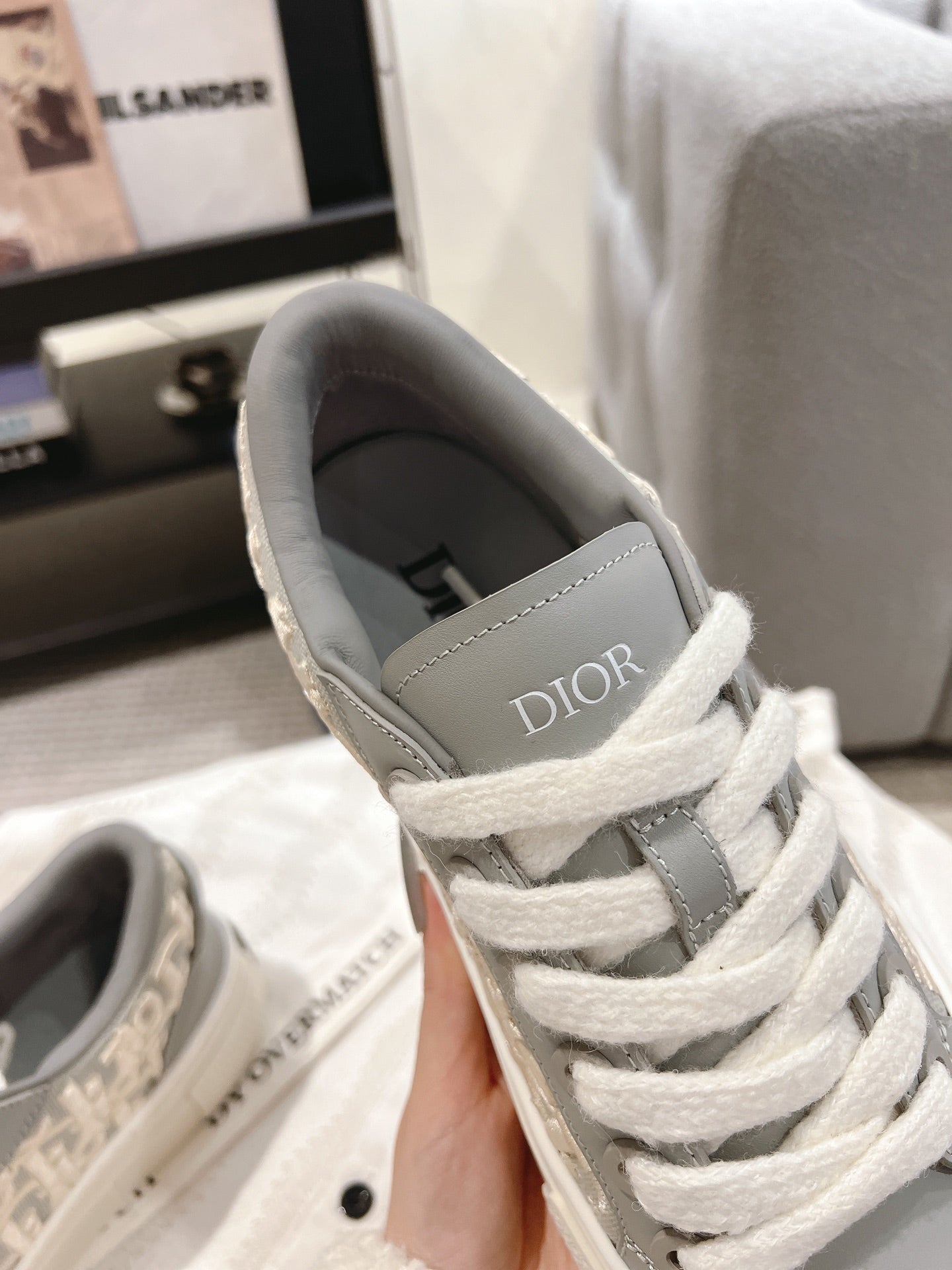 White lace-up sneaker close-up with gray interior lining and DIOR logo on heel