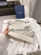 Gray Dior monogram low-top sneakers held in hand with white laces and sole