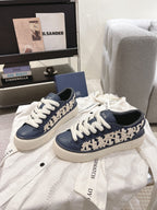 Pair of navy low-top sneakers with white laces, patterned side trim, and chunky sole