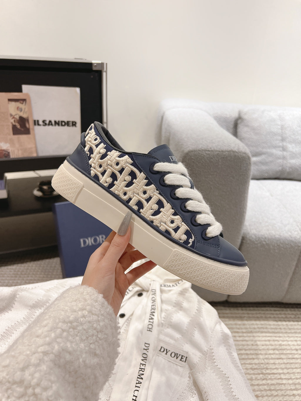 Navy and beige low-top sneakers with white laces and repeating logo print on sides