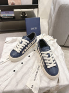 Navy and white low-top sneakers with white laces and embroidered logo around the sides