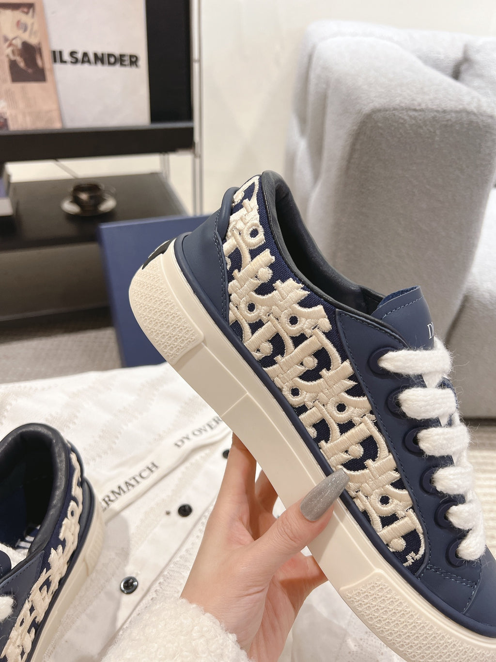Navy low-top sneaker with white laces and beige logo embroidery on the side
