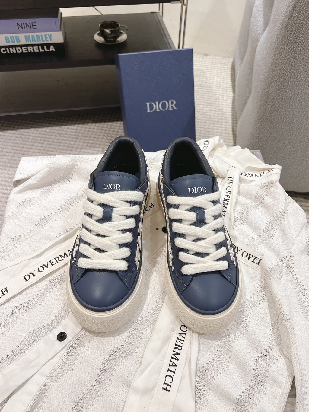 Navy and white low-top sneakers with white laces and embroidered Dior logo tabs
