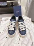 Navy and white low-top sneakers with white laces and embroidered Dior logo tabs