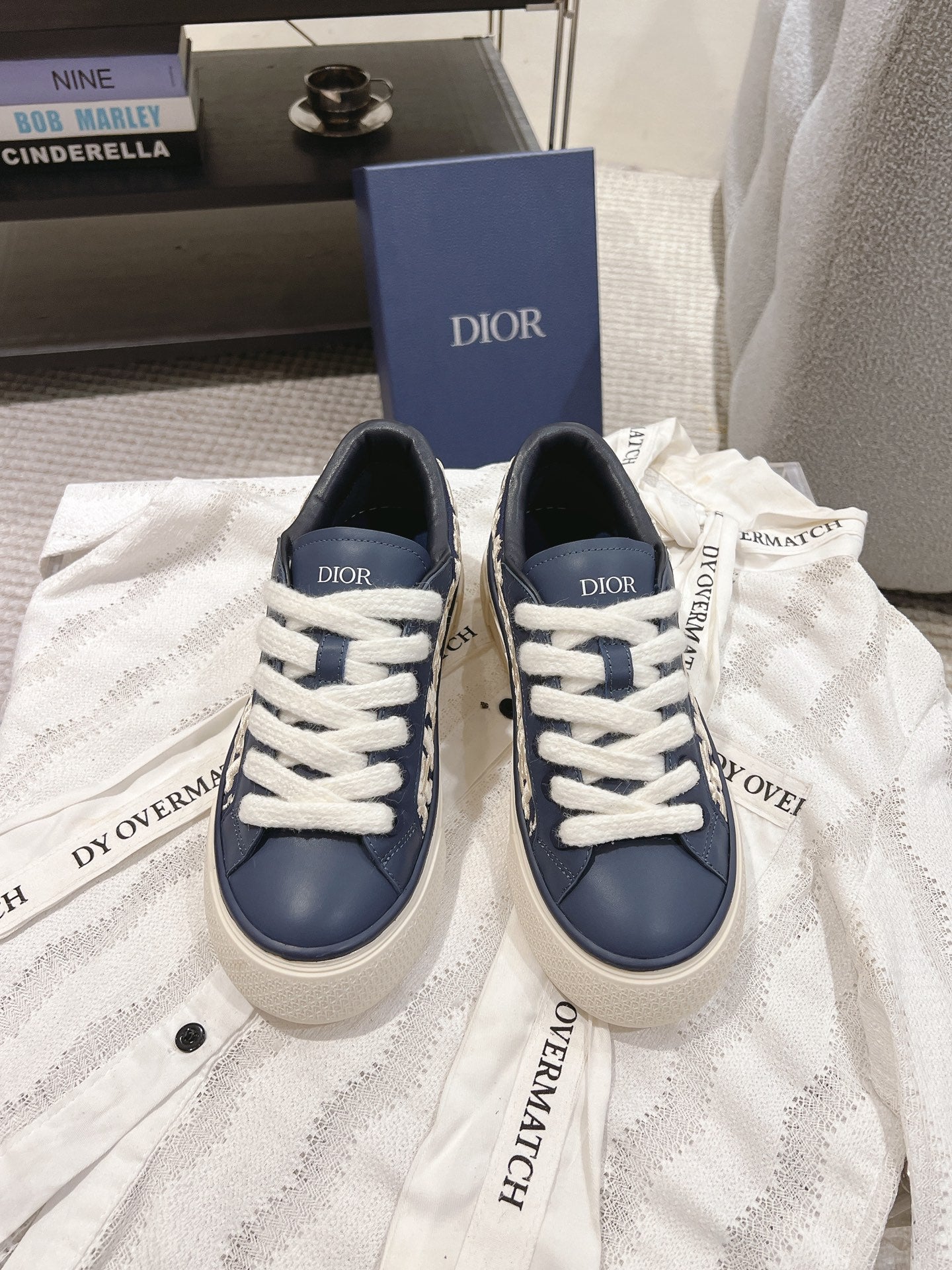 Navy and white low-top sneakers with white laces and embroidered Dior logo tabs