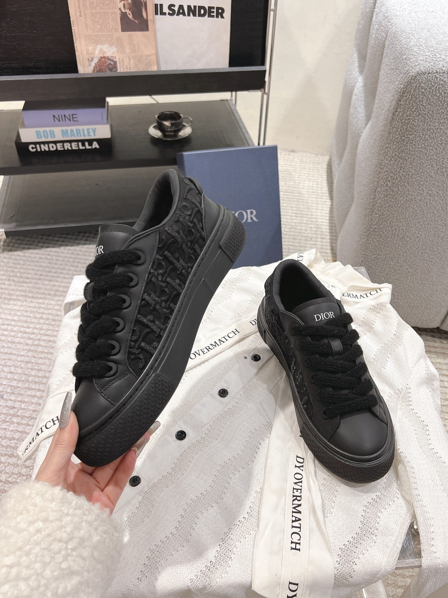 Black Dior sneakers with thick sole and embossed pattern on sides.