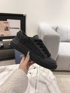 Black lace-up Dior sneakers, side view with textured upper and black sole.