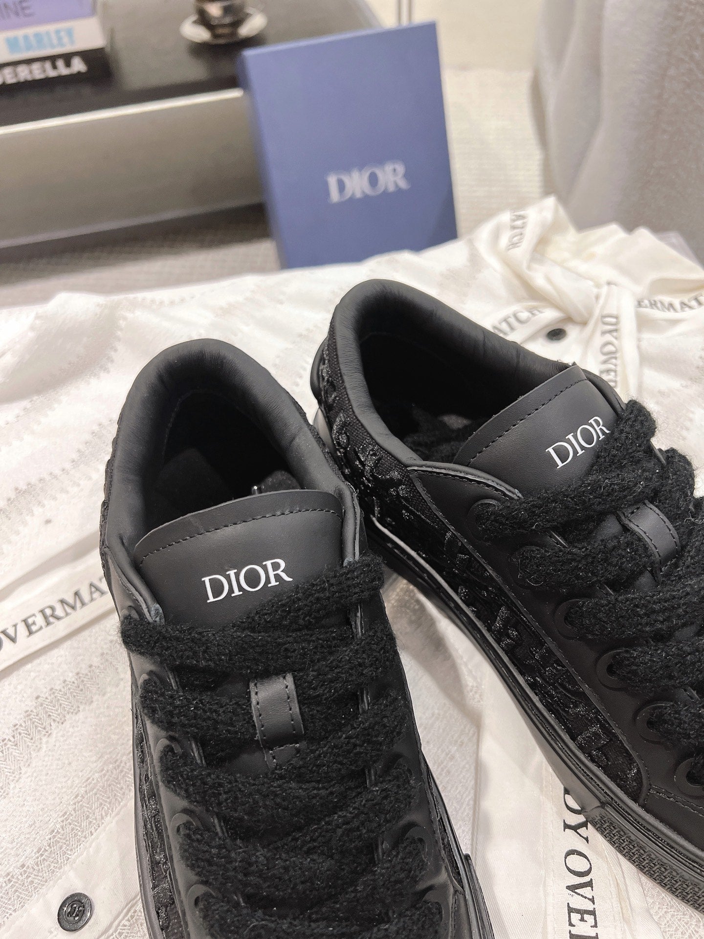 Black Dior sneakers with strap-like panels and Dior logo on each outer side.