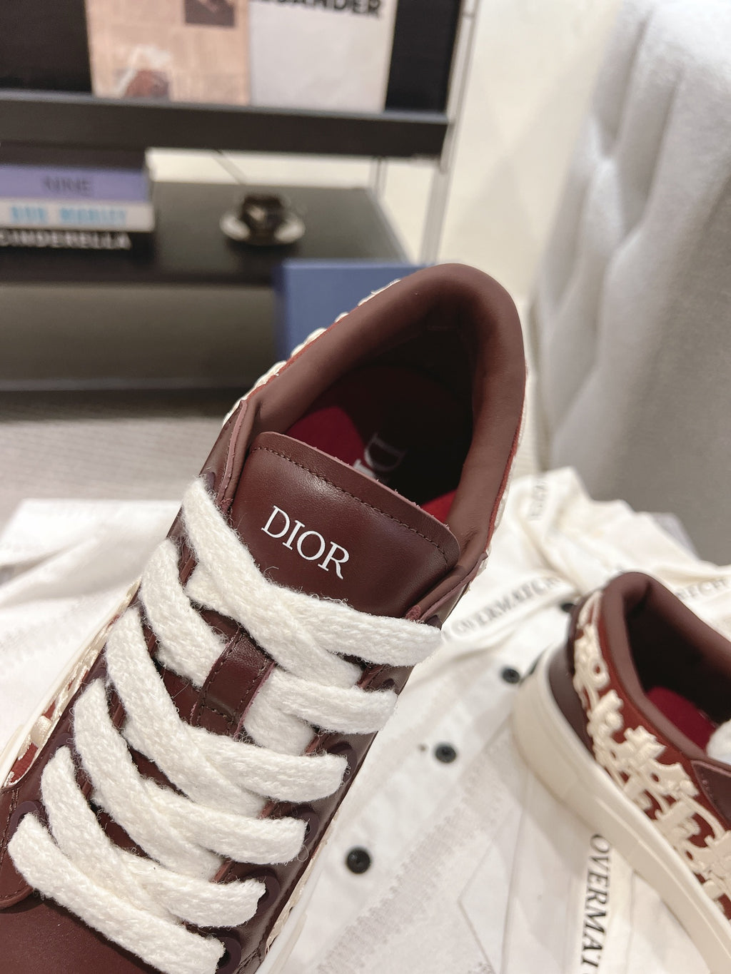 Dior unisex sneakers close-up, dark brown leather with white laces and Dior logo tongue