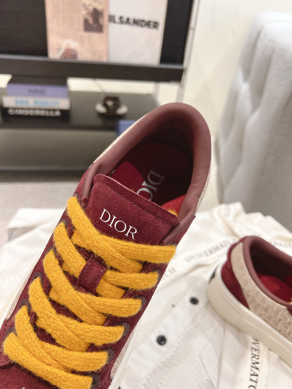 Burgundy sneaker heel with yellow laces and Dior logo patch, close-up.