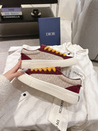 Burgundy and cream patterned low-top sneakers with yellow laces and white sole, stacked.