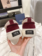 Burgundy low-top sneakers with 'Dior' heel labels and yellow laces, back view.