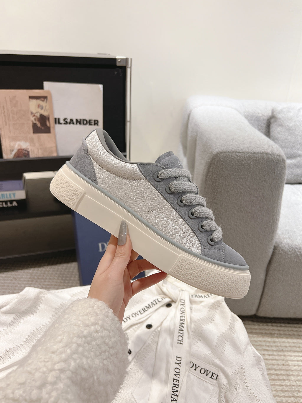 Gray Dior unisex lace-up sneaker on hand, side view, off-white sole