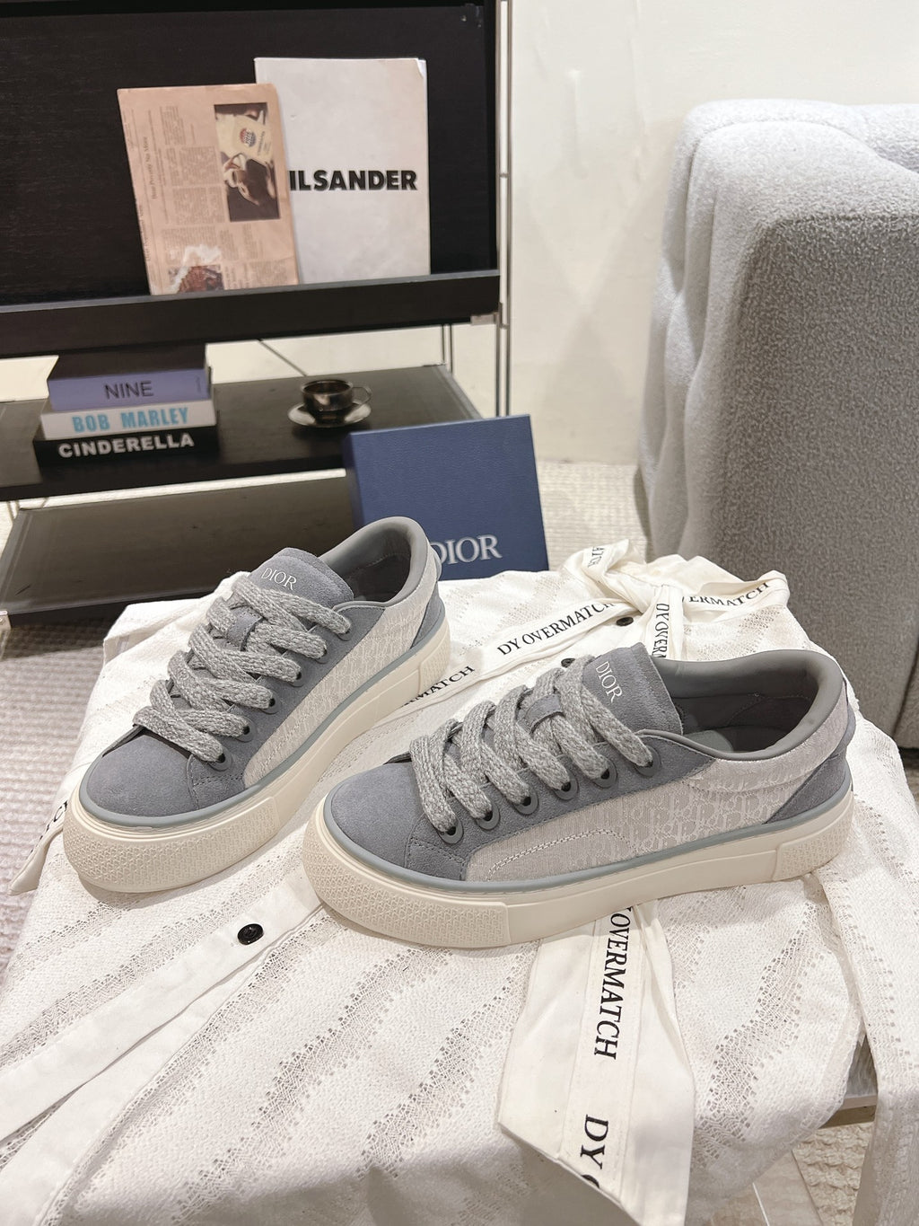 Pair of gray Dior unisex lace-up sneakers on white cloth, off-white sole