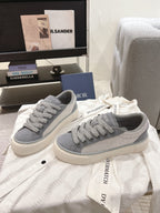 Pair of gray Dior unisex lace-up sneakers on white cloth, off-white sole
