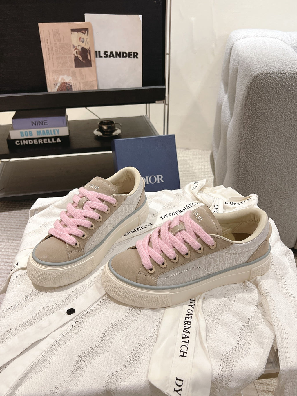 Pair of low-top sneakers in light beige with pink shoelaces and branded side trim